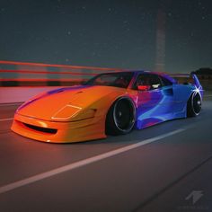 an orange and blue sports car driving down the road at night with its lights on