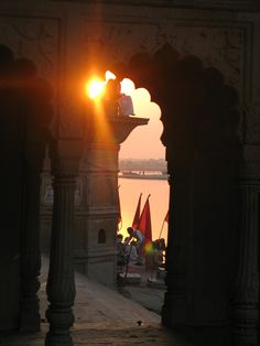 the sun is setting behind an archway