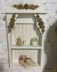 a white shelf with shoes and jars on it