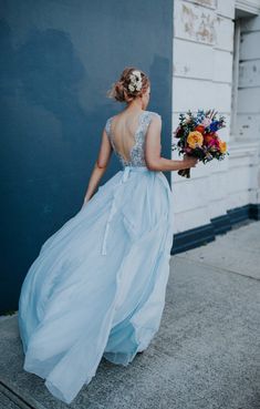 a woman in a blue dress is walking down the street with her back to the camera