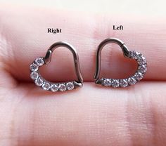 a pair of silver heart shaped earrings with clear stones on the inside and outside of them