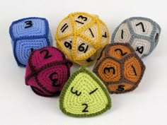 crocheted dices with numbers and faces are arranged in a row on a white surface