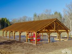 a large wooden structure sitting in the middle of a dirt field next to some trees