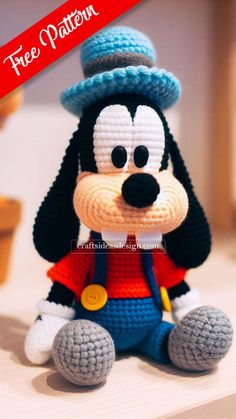 a crocheted mickey mouse sitting on top of a white table next to a red sign