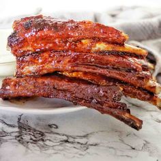 a stack of ribs sitting on top of a white plate