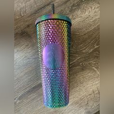 a starbucks cup with a purple and blue design on the lid sitting on a wooden table