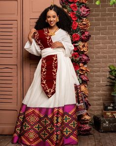 This stunning dress is a true masterpiece of Ethiopian textile art. The main fabric of the dress is made from Menen, a high-quality Ethiopian cotton known for its softness, durability, and lustrous sheen. The Menen fabric adds a touch of luxury to the dress, making it perfect for special occasions. The lower part of the dress is fully handwoven from menen, a fabric known for its intricate patterns and rich texture. The shimmering material adds a touch of elegance and movement to the dress, makin Festive Dresses For Traditional Ceremonies With Weaving Work, Traditional Ceremony Dress With Weaving Work For Festivals, Ceremonial Dresses With Weaving Work For Festivals, Red Dresses With Traditional Patterns For Ceremonies, Ceremonial Dresses With Woven Motifs For Transitional Season, Traditional Red Maxi Dress For Eid, Traditional Red Dresses For Eid, Traditional Red Ceremonial Dress, Ceremonial Red Dress With Traditional Patterns