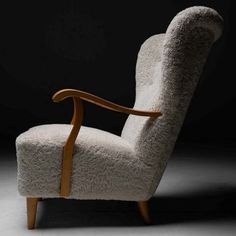 a chair made out of sheepskin with wooden arms and legs, on a black background