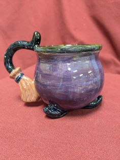 a purple vase sitting on top of a red cloth next to a small wooden pipe