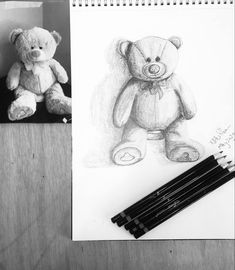 a pencil drawing of a teddy bear next to some black and white crayons