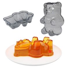 two bear shaped ice cream molds on a white plate with an orange one in the middle