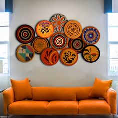 an orange couch sitting in front of a white wall with lots of plates on it