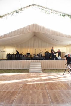 A wooden dance floor in front a white, lavishly draped stage under an outdoor event tent. Tent Design Ideas, Event Tent Design, Outdoor Wedding Setup, Wooden Dance Floor, Mexico City Wedding, Staging Decor, First Dance Photos, City Wedding Venues, Dance Floor Wedding