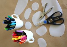 scissors and markers are sitting on a paper towel next to a cup with holes in it