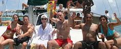 a group of people sitting on the back of a boat waving at the camera with their hands in the air