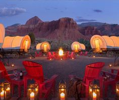 a group of red chairs sitting next to each other in front of a fire pit