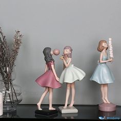 three little figurines are standing on a shelf next to vases and flowers