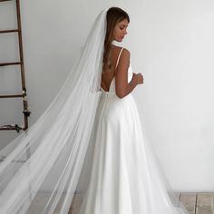 a woman wearing a white wedding dress with a long veil on her head and back