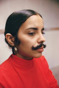 a woman with a fake moustache on her face is looking off to the side