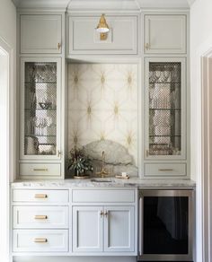 a kitchen with white cabinets and gold hardware on the cupboards is pictured in this image