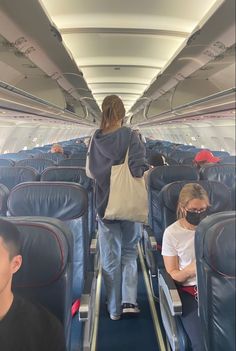 people sitting in seats on an airplane with their backs turned to the side and one person holding a bag