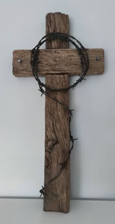 a wooden cross with barbed wire around it on a white surface, against a gray wall