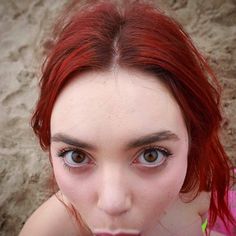 a woman with red hair and blue eyes posing for the camera