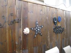 a wooden fence with some metal stars and flowers on it's side, next to a white chair