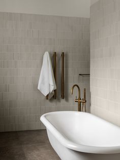 a white bath tub sitting next to a wall mounted faucet in a bathroom