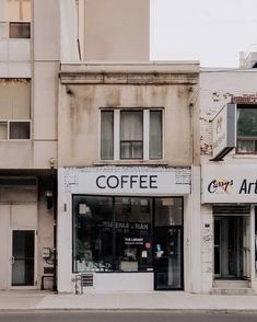 an empty street corner in front of a building with coffee shops on the side and windows