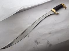 a knife that is laying on top of a piece of paper with a gold handle