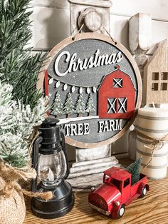 a christmas tree farm sign sitting on top of a table next to a red truck