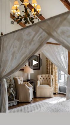 a canopy bed sitting in the middle of a living room next to a couch and chair