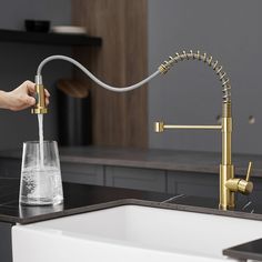 a person pouring water into a glass from a faucet in a kitchen sink