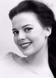 a black and white photo of a woman with her hair in a ponytail smiling at the camera