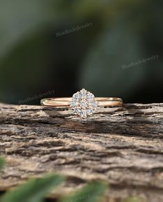 an engagement ring with three diamonds on top of it sitting on a piece of wood