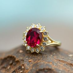 a close up view of a ring with a large red stone surrounded by small white stones