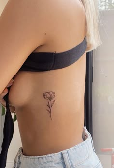 a woman with a flower tattoo on her stomach and side view mirror in the background