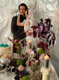 a man and woman standing next to each other in front of a table with flowers