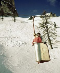 two people riding on a ski lift in the snow