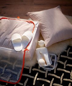 two pairs of white slippers sitting on top of a black rug next to pillows