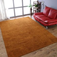 a living room with a red leather couch and brown rug on top of the floor