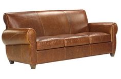 a brown leather couch sitting on top of a white floor