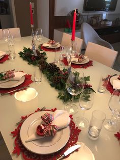 the table is set for christmas dinner with red and green decorations