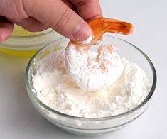 a person is dipping something into a bowl with powdered sugar on top and an orange peel in the middle