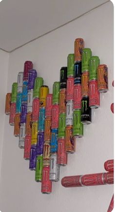 colorful cans are arranged in the shape of a heart on a white wall with red and green crayons