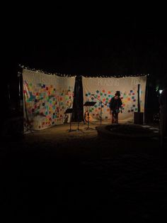 a man standing in front of a wall covered in confetti and balloons at night