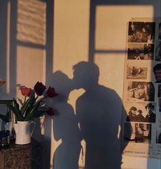 the shadow of a man standing next to a vase with flowers