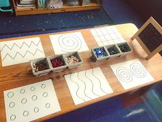 a wooden table topped with lots of different types of shapes and lines on paper next to boxes filled with rocks