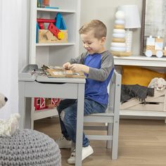 a young boy sitting at a table playing with toys